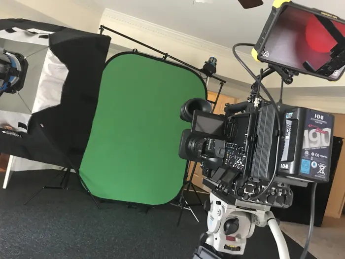 A camera in front of a green screen with a light kit
